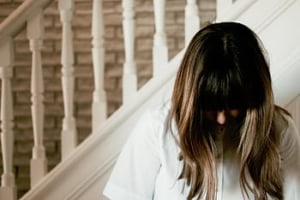 Woman with head bowed, hair covering face